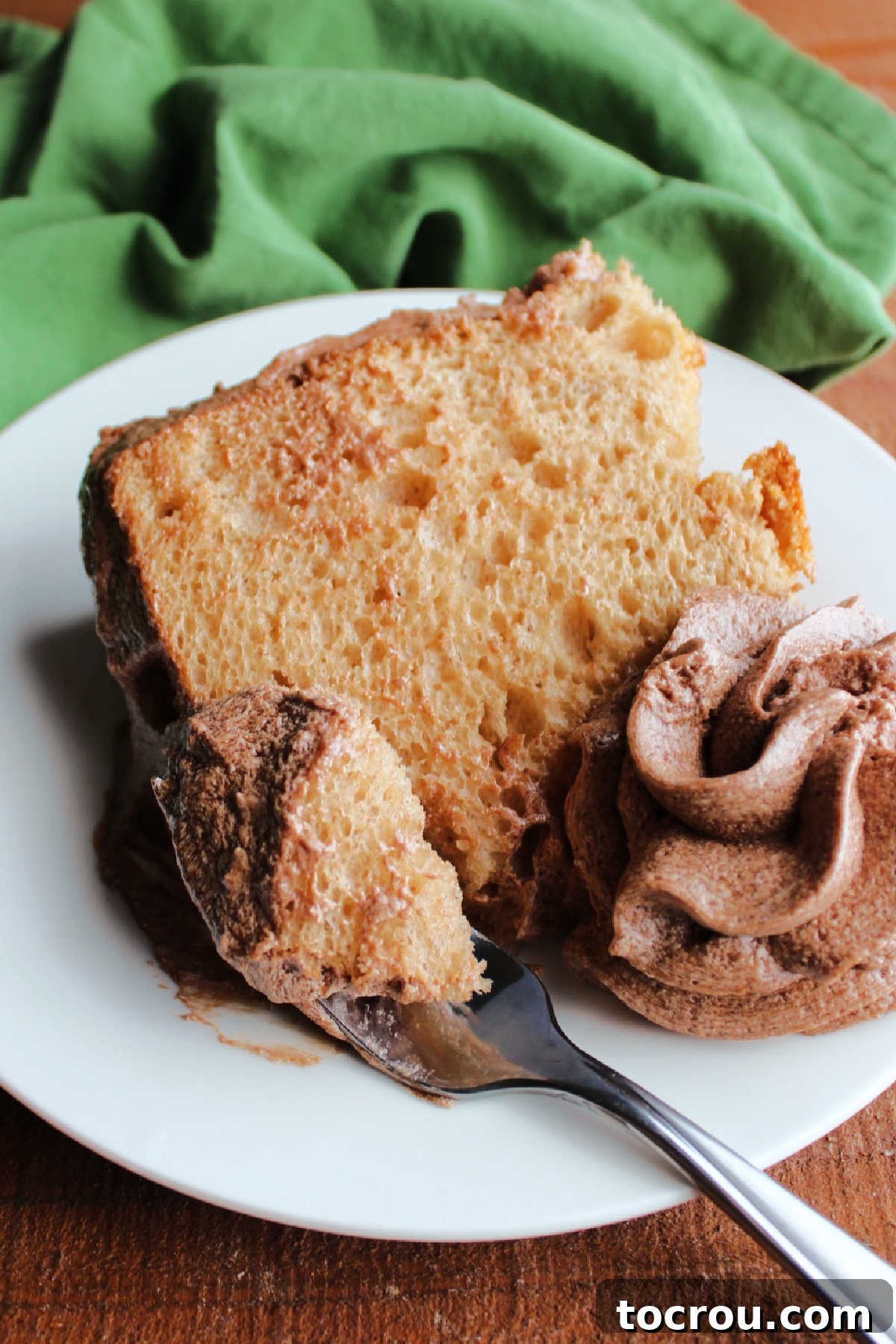 Velvet Mocha Cloud Frosting 3 Bite of coffee angel food cake on fork with swirl of mocha mousse frosting acting as a garnish on the plate.