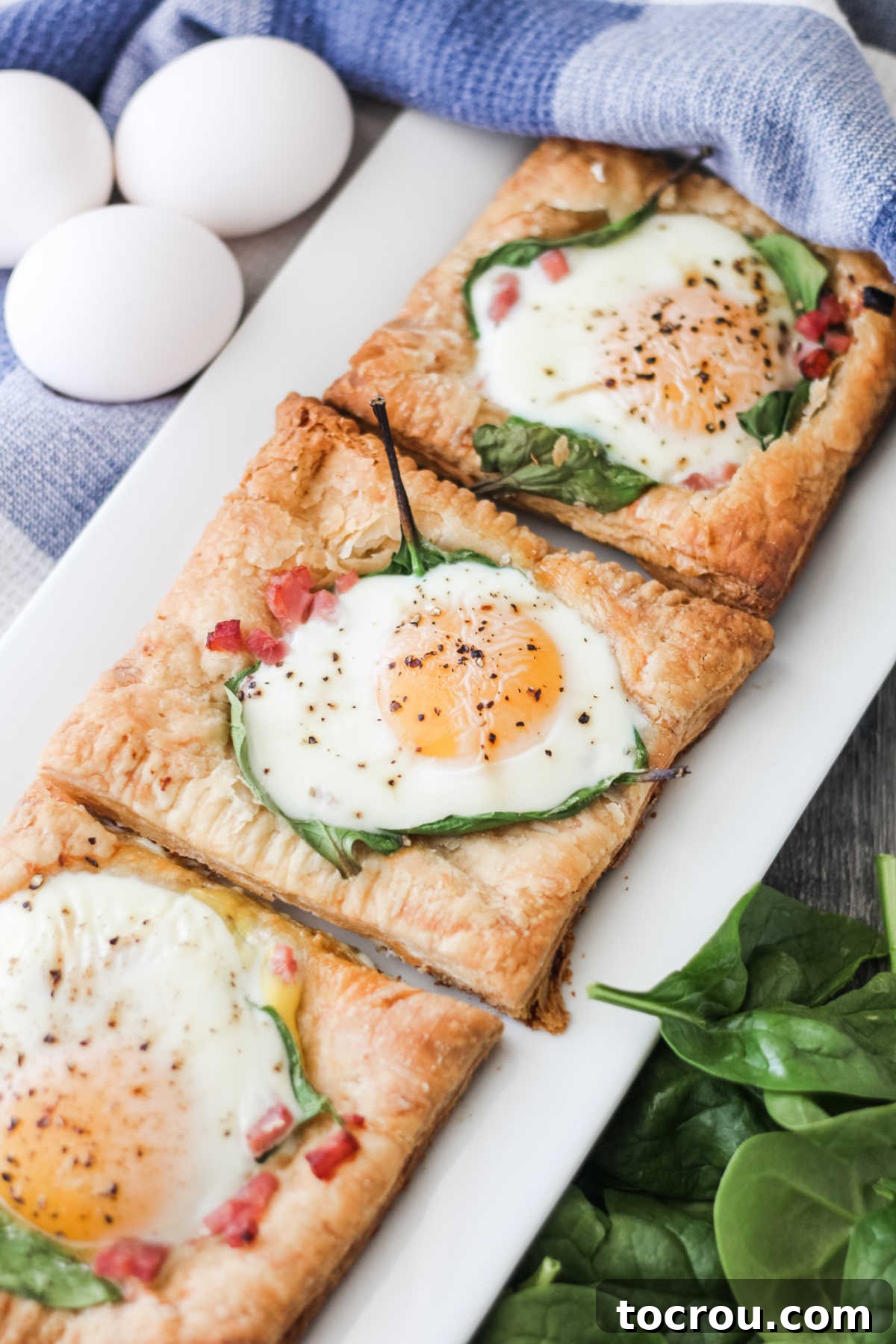 A beautiful platter of golden puff pastry tarts, each baked to perfection with ham, spinach, and a sunny-side-up egg.