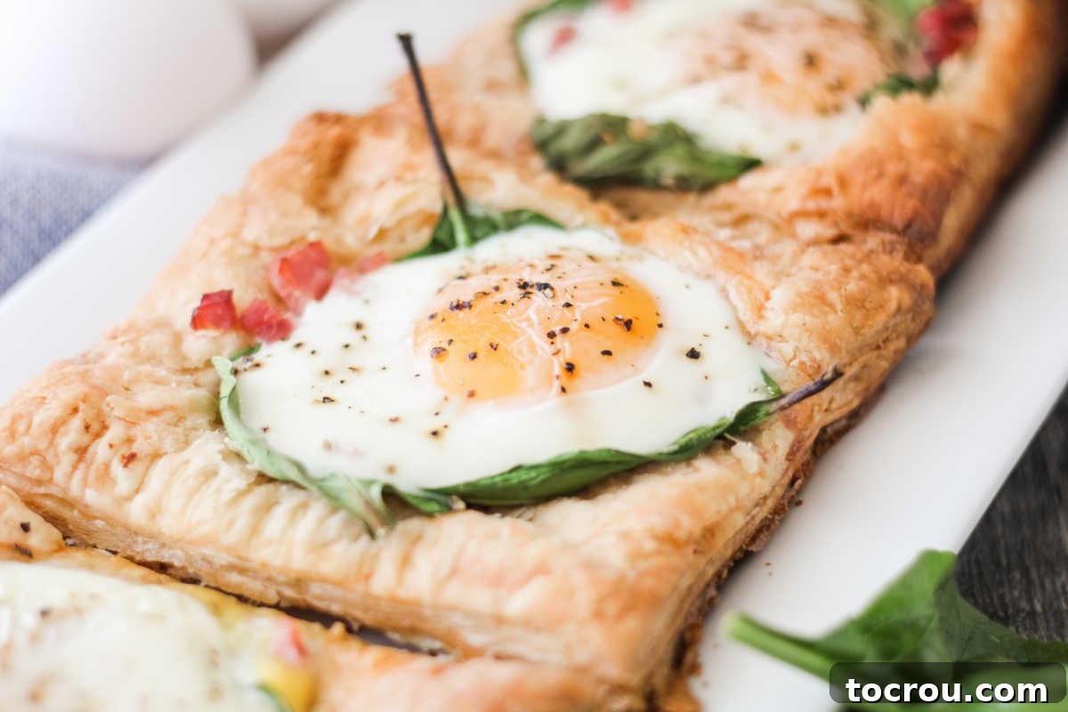 A platter showcasing multiple puff pastry tarts, perfectly golden and topped with eggs, spinach, and ham, ready for Hollandaise.