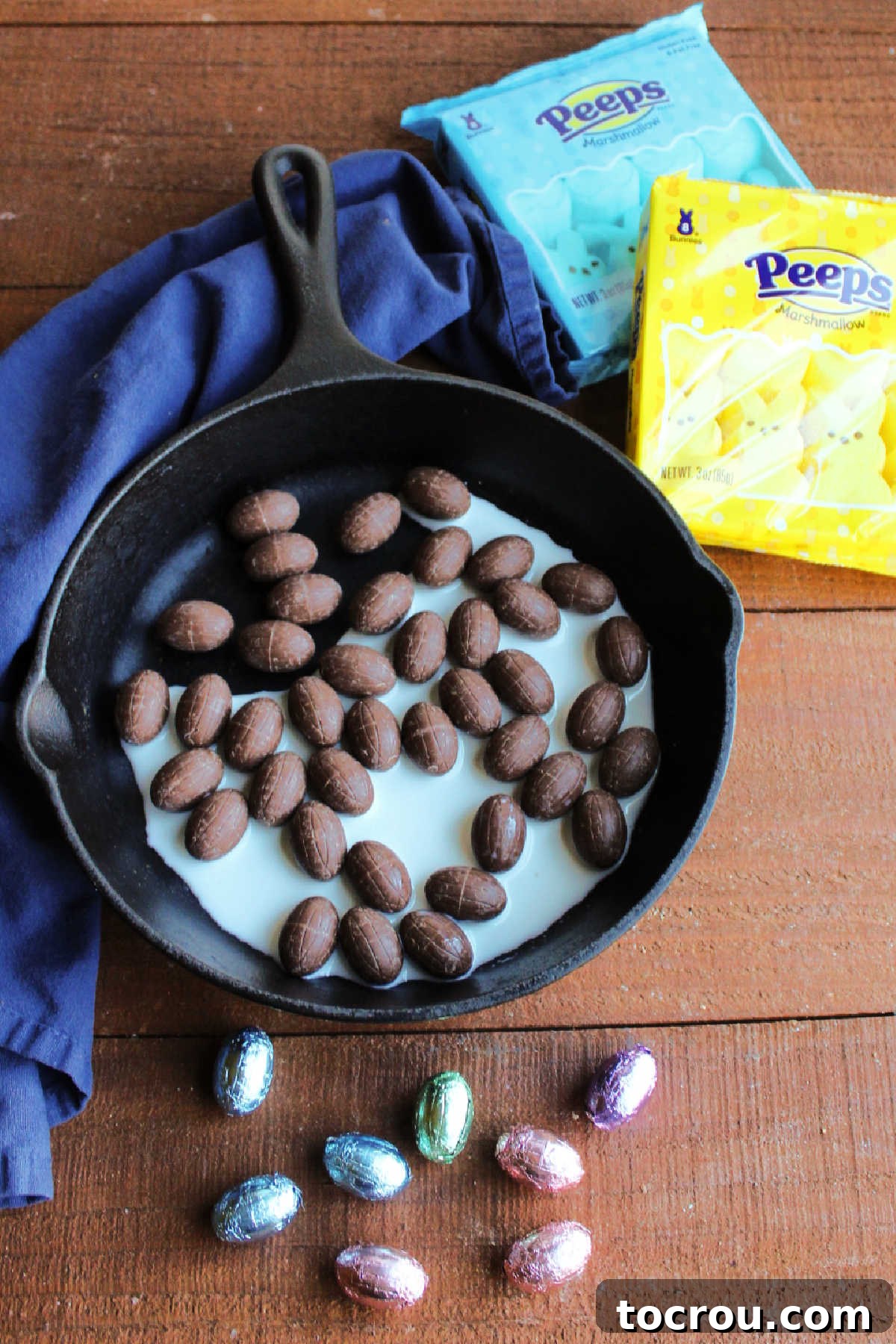 Chocolate Eggs and Peeps for S'mores Dip Small chocolate eggs in a pan with some milk next to a couple of packages of bunny shaped Peeps marshmallows.