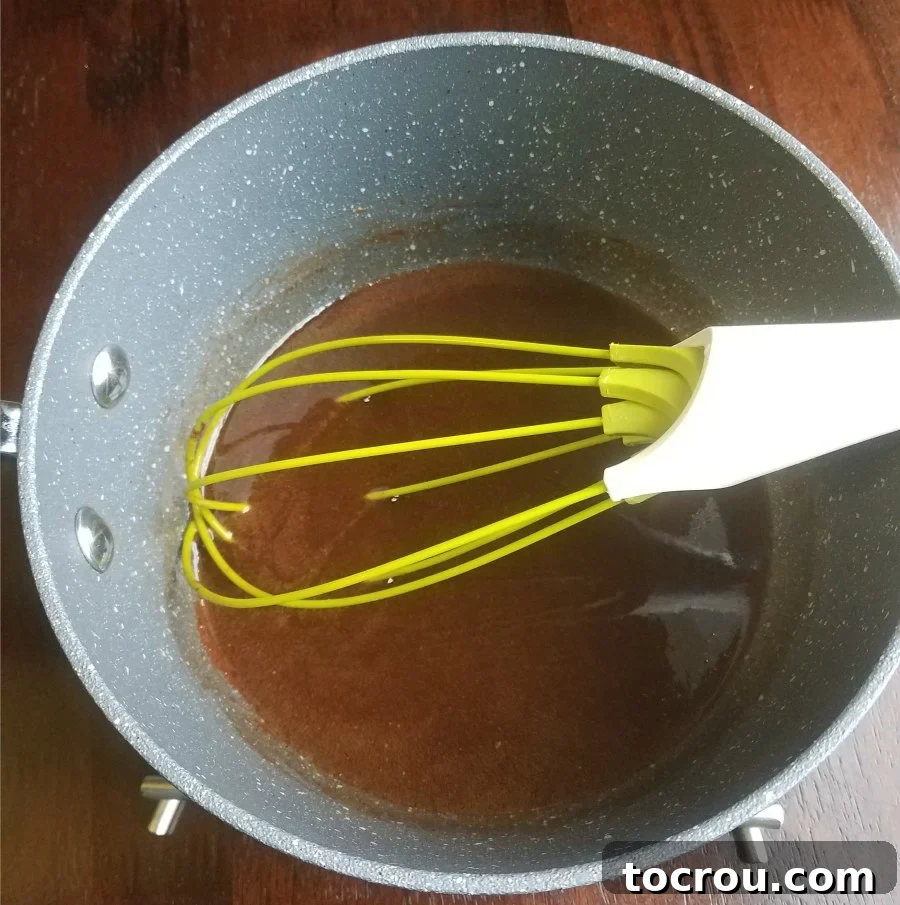 Saucepan filled with rich, glossy brownie batter, a whisk resting inside, illustrating the one-pan preparation.