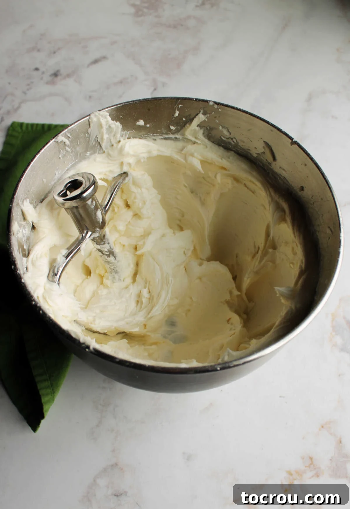Mixer bowl brimming with smooth, white crusting buttercream, perfectly prepared for cake and cookie decoration.