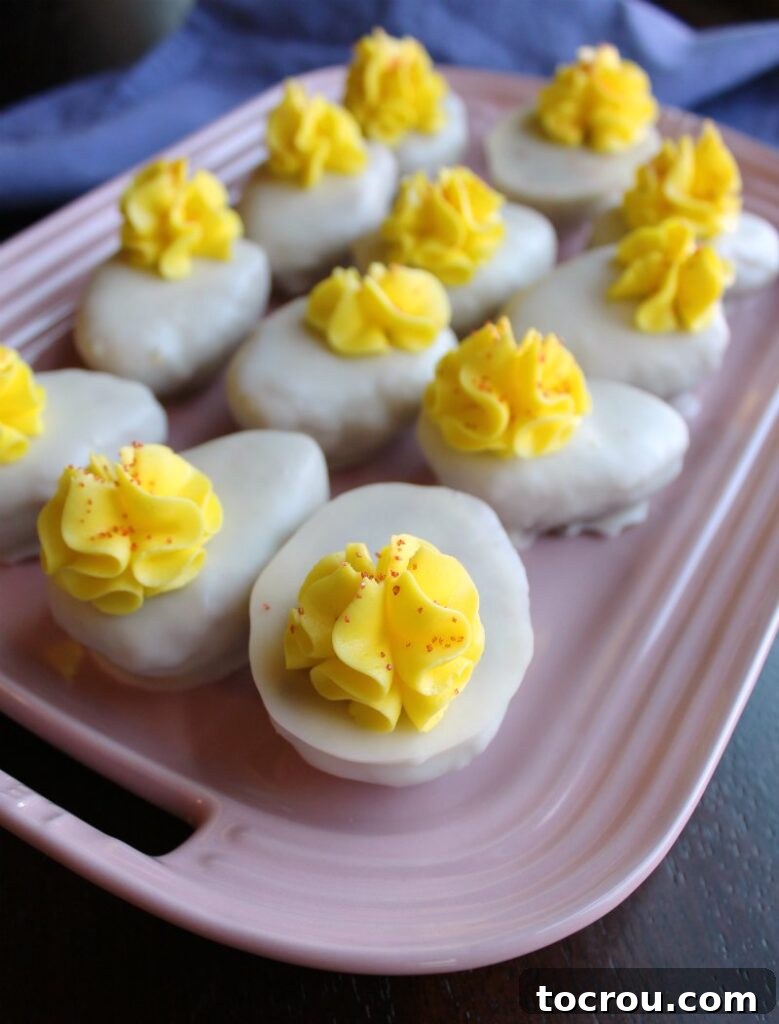 Pink serving platter generously filled with whimsical deviled egg shaped cake balls, each meticulously frosted.