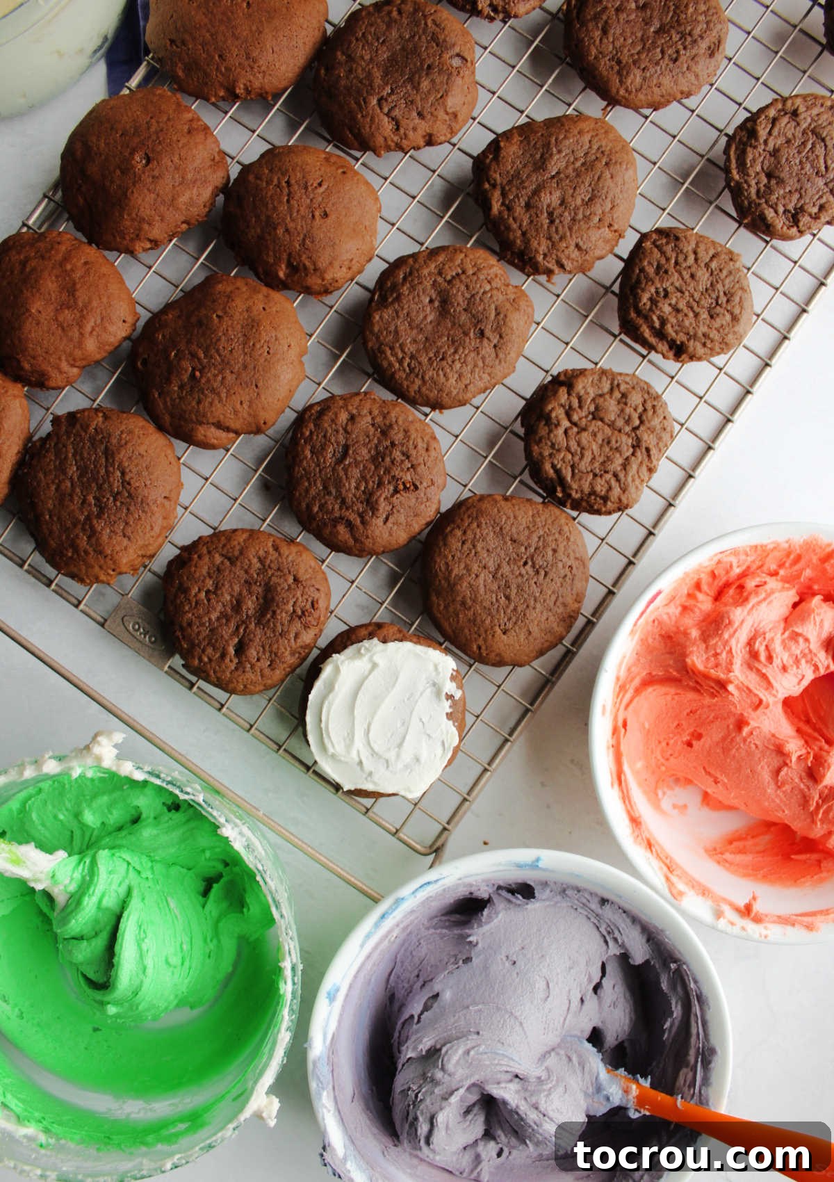 Applying creamy buttercream frosting onto freshly baked, cooled chocolate sour cream cookies.
