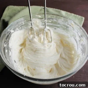 Glass mixing bowl filled with creamy cream cheese frosting ready to use.