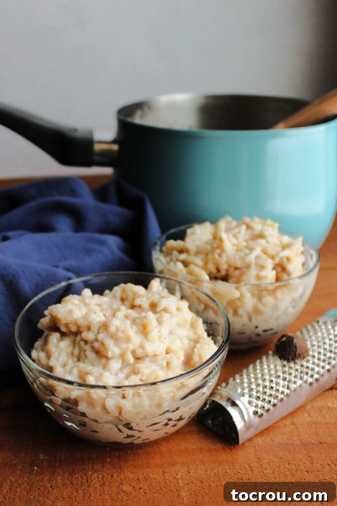 Golden Banana Rice Pudding 4 small bowls of banana honey rice pudding with nutmeg grater in front of teal saucepan.