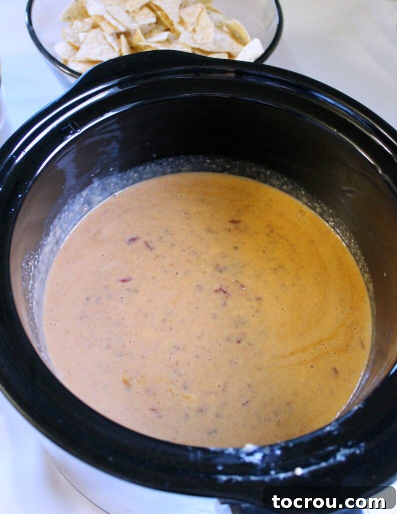 Kickoff Queso Sensation 3 A slow cooker filled with steaming tailgate queso, perfectly melted and ready to be served, promising a delightful treat for any gathering.