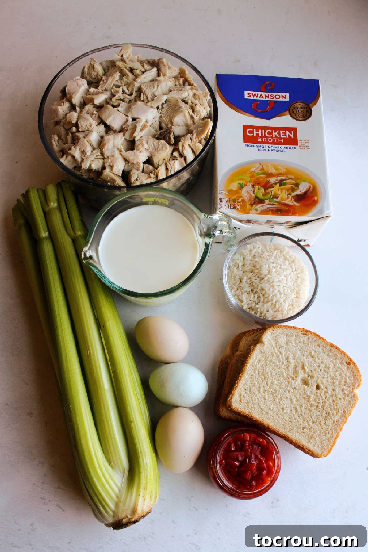 Comforting Turkey and Rice Casserole with Rich Gravy 2 All fresh ingredients for the turkey and rice casserole laid out: cooked turkey, uncooked rice, milk, eggs, chopped celery, cubed bread, and chicken stock.