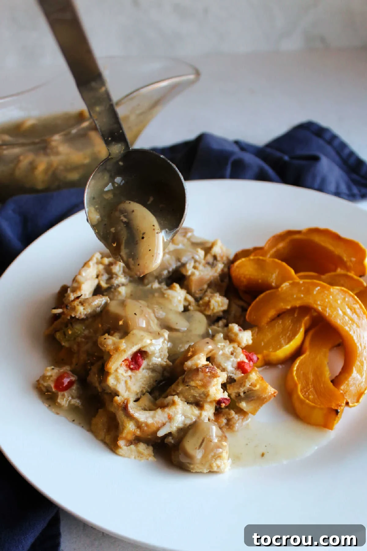 Comforting Turkey and Rice Casserole with Rich Gravy 7 A hand ladling thick mushroom gravy generously over a portion of turkey casserole, highlighting its rich texture.