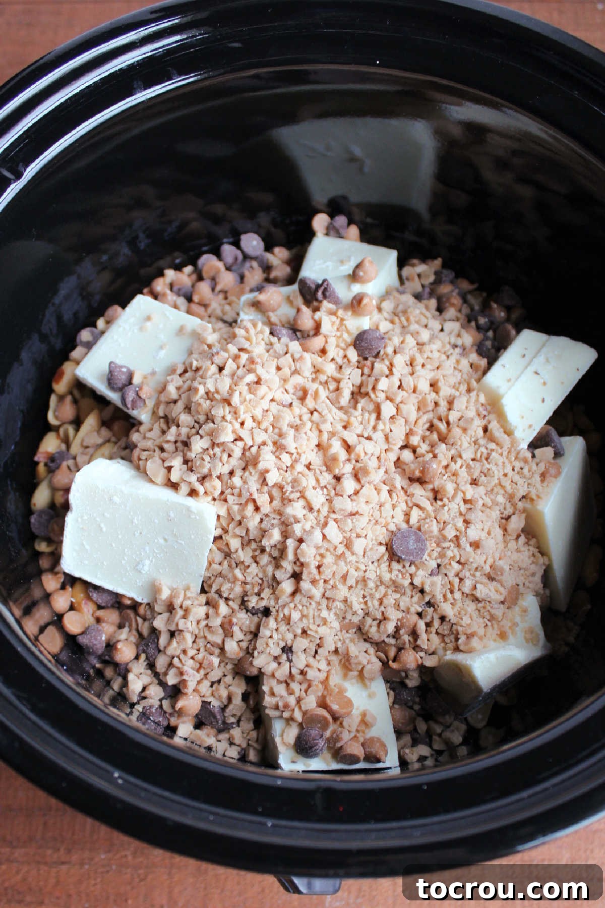 Effortless Crockpot Peanut Delights 4 Slow cooker filled with peanuts, almond bark, chocolate chips and toffee bits ready to cook.
