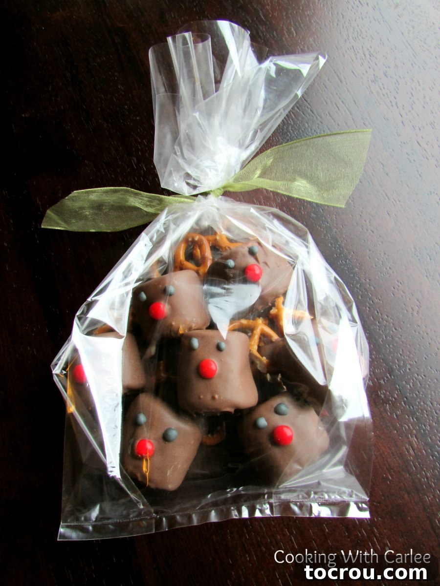Jolly Reindeer Marshmallow Delights 2 Cellophane bag filled with chocolate dipped marshmallows decorated to look like rudolph the red nosed reindeer tied with a bow ready to be gifted.