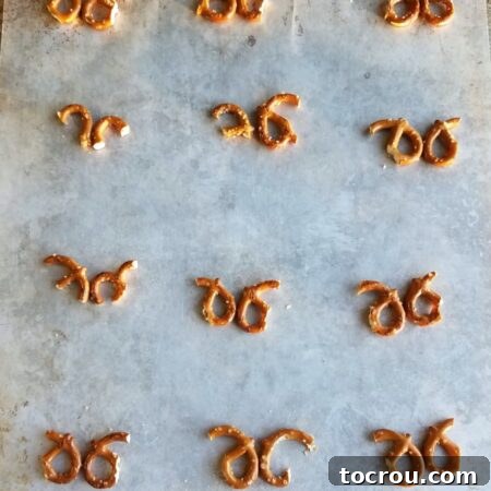 Jolly Reindeer Marshmallow Delights 5 Pieces of mini pretzels arranged to look like antlers on baking tray waiting for chocolate and marshmallows.