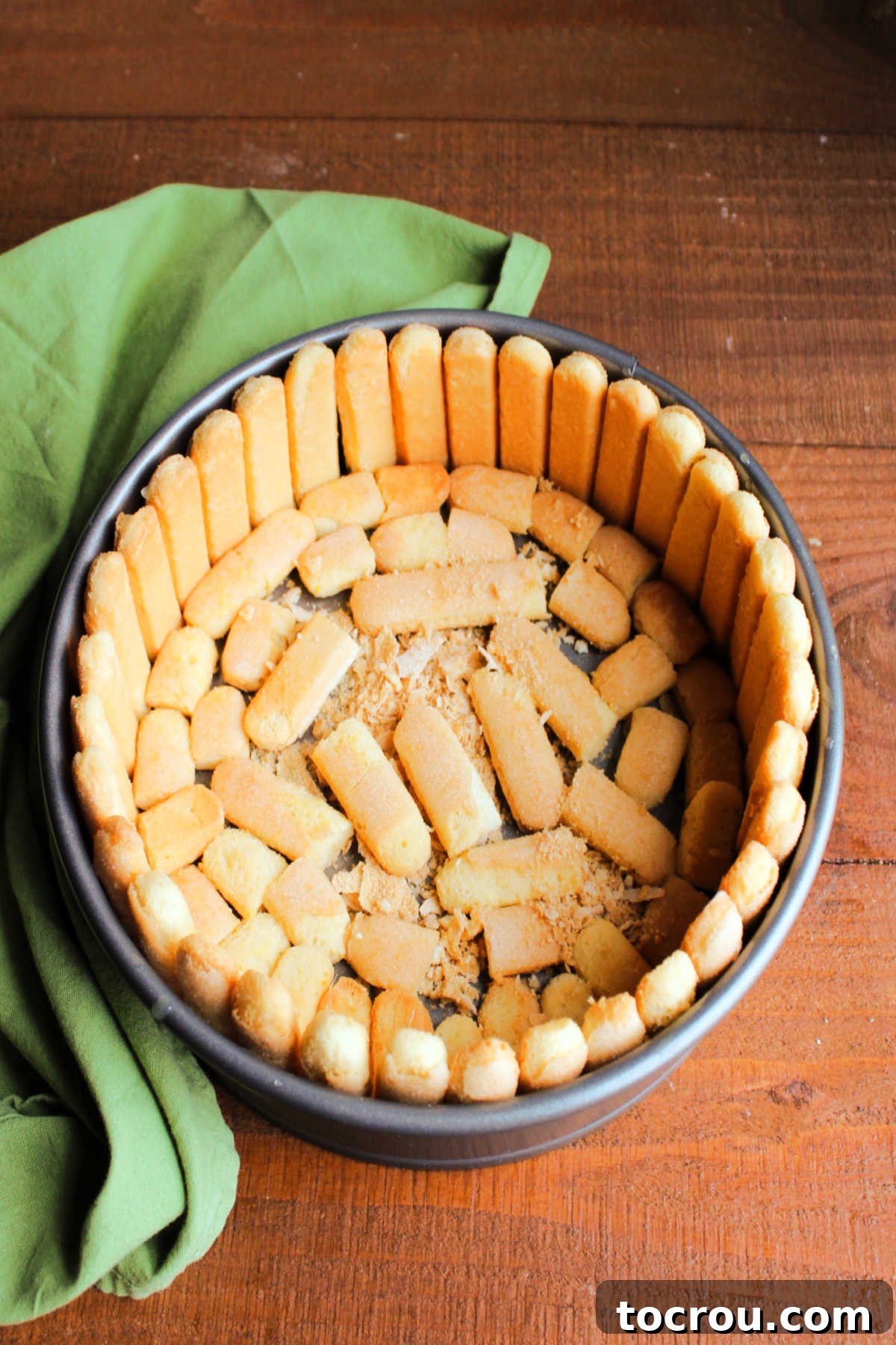 Lady fingers dipped in orange juice and arranged in springform pan to make the exterior of the Charlotte Russe.
