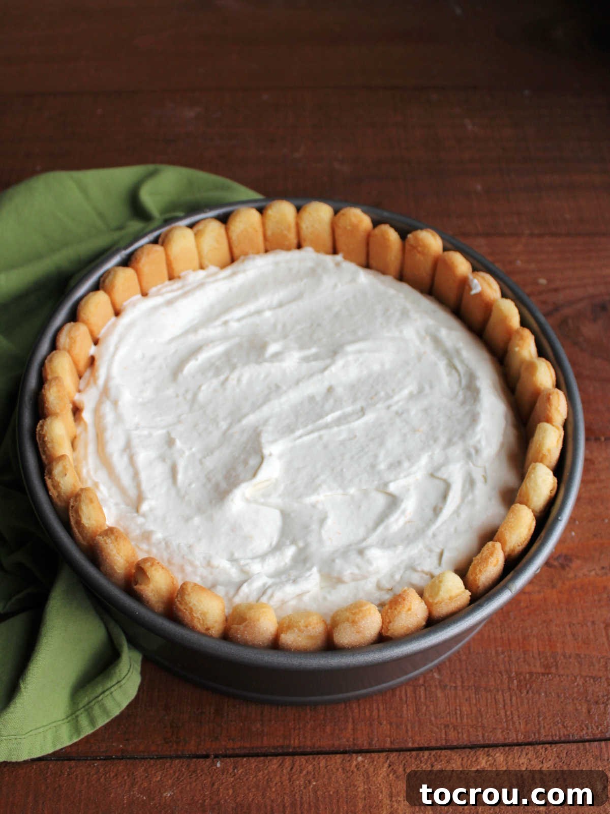 Creamy filling spread inside the lady finger crust in the springform pan.