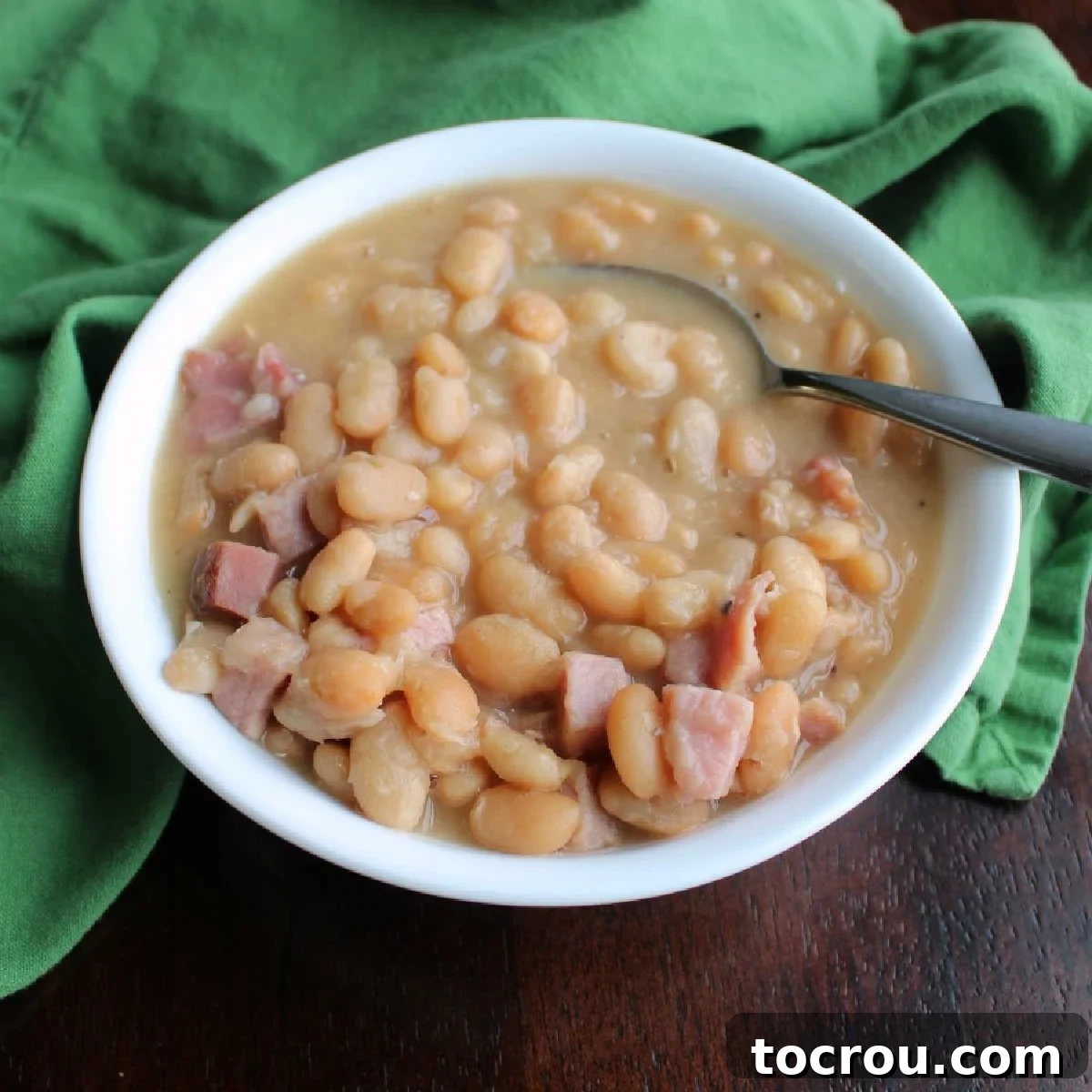 Hearty Slow Cooker Ham and Bean Soup A beautiful bowl of slow cooker ham and bean soup, ready to be enjoyed, with a rich, thick broth and tender beans.