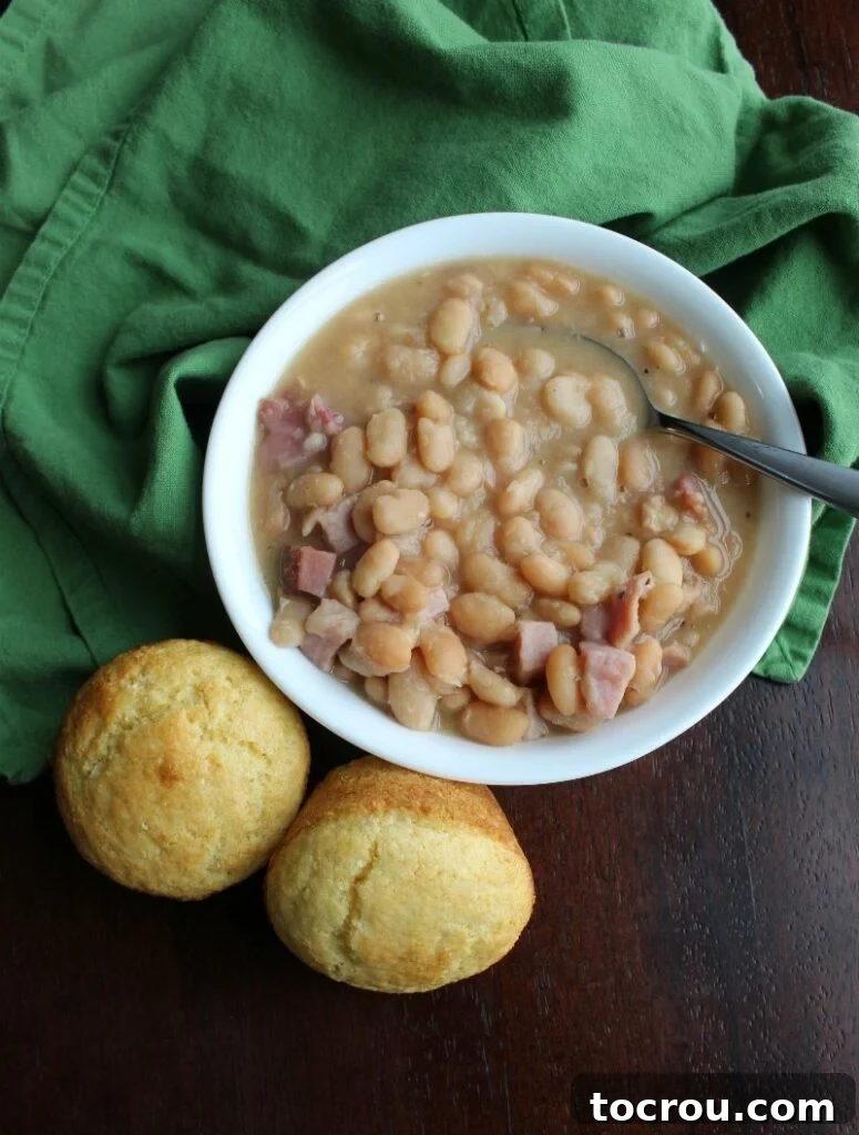 Ham and Beans with Corn Muffins A comforting bowl of ham and beans, perfectly cooked and garnished, placed next to fluffy corn muffins, inviting a warm, home-cooked meal.