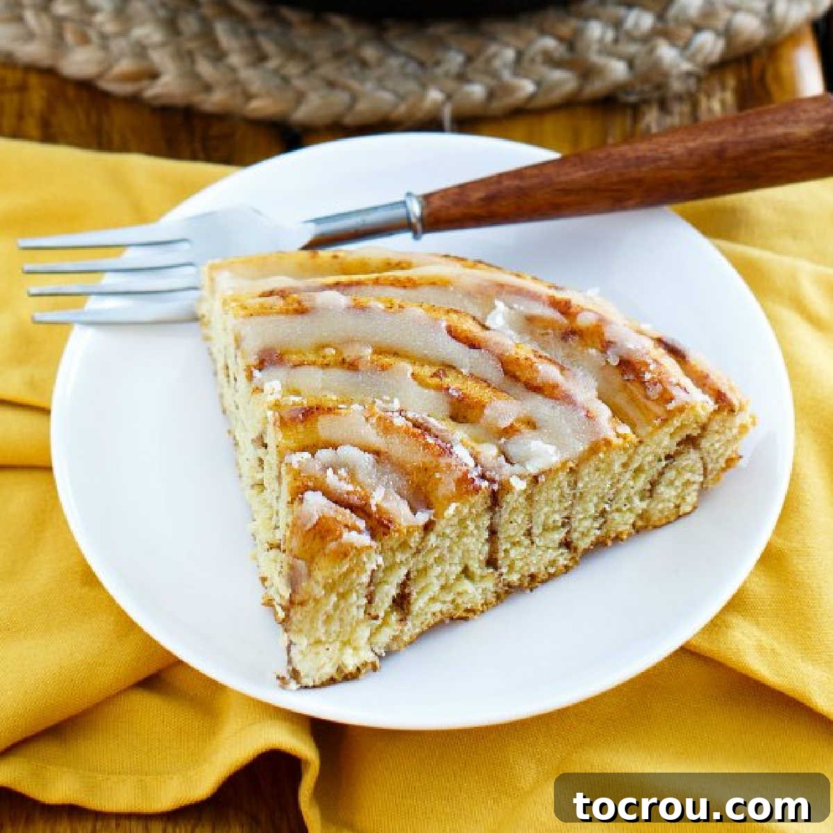 Golden Brown Butter Maple Glaze 2 Big slice of pumpkin spice cinnamon roll cake drizzled with rich maple browned butter glaze on a plate with a fork, ready to be enjoyed.