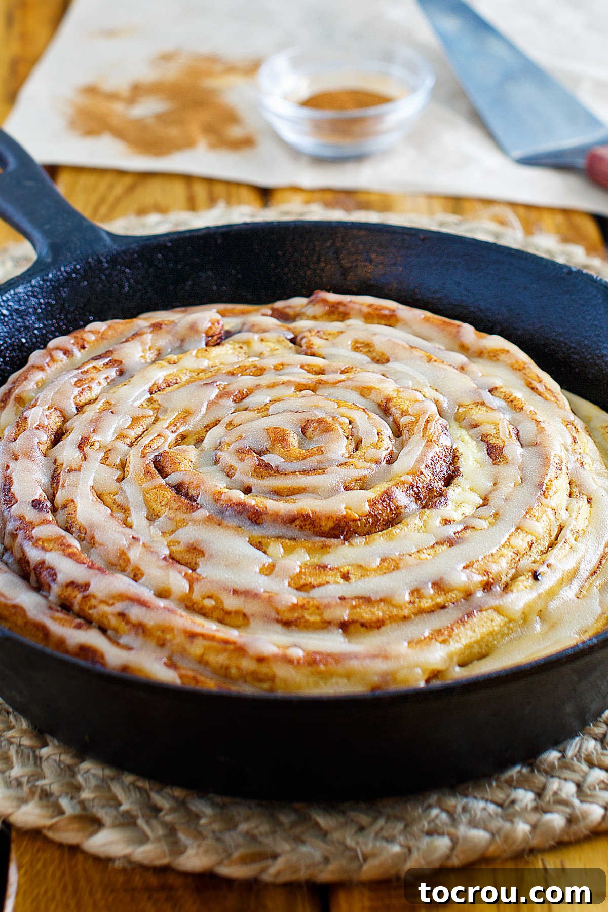 Golden Brown Butter Maple Glaze 4 A close-up view looking across the top of a freshly baked pumpkin spice skillet cinnamon roll, glistening with yummy maple brown butter glaze.
