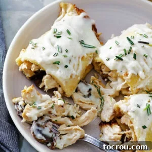 Forkful of creamy lemon bechamel covered chicken and mushroom stuffed crepes.