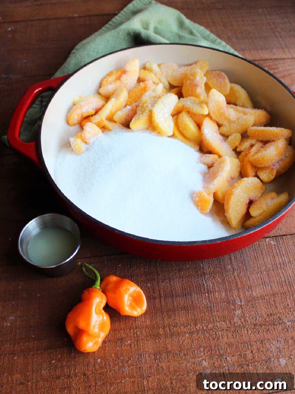 Ingredients including frozen peach slices, white sugar, habanero peppers, and lemon juice ready to be made into jam.