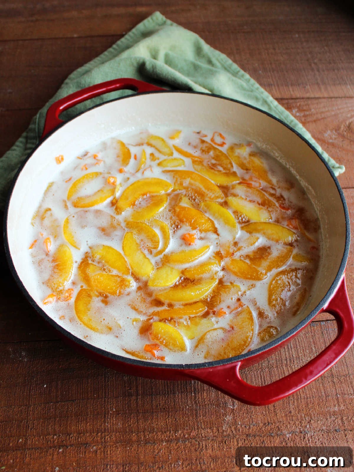 Cooked peaches with bits of habanero in a pan, ready to be processed.