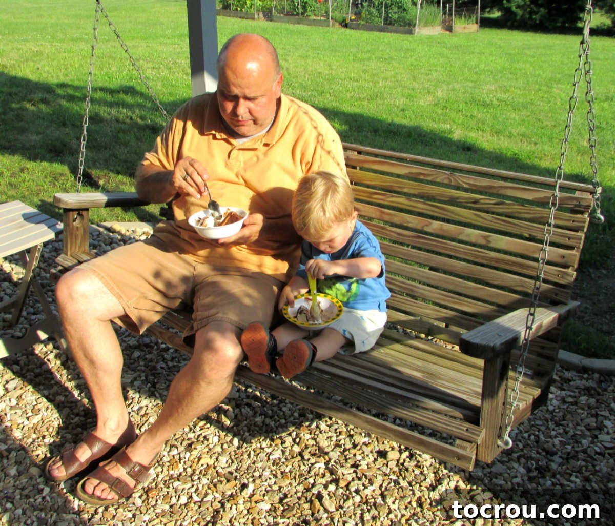 grandpa and grandson eating cake and ice cream on a porch swing.