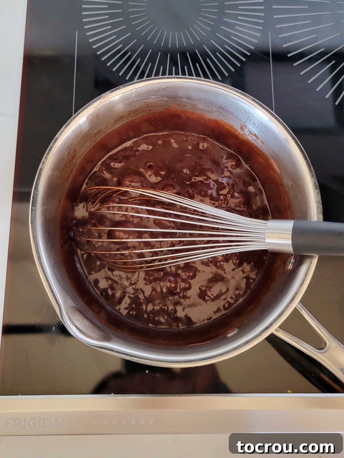 Smooth, rich chocolate fudge icing bubbling gently in a saucepan on a stove, indicating it's reached the perfect boiling point.