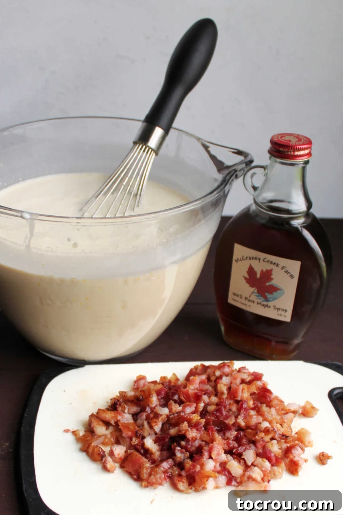 Maple Bacon Bliss Ice Cream 3 Big glass bowl of ice cream base next to a pile of chopped bacon and bottle of maple syrup.