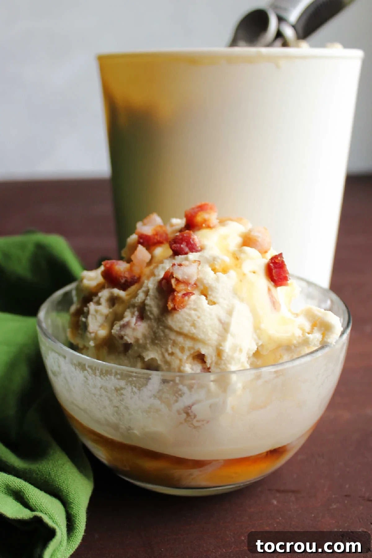 Maple Bacon Bliss Ice Cream 6 Looking across bowl of maple bacon ice cream topped with bits of crisp bacon and extra maple syrup.