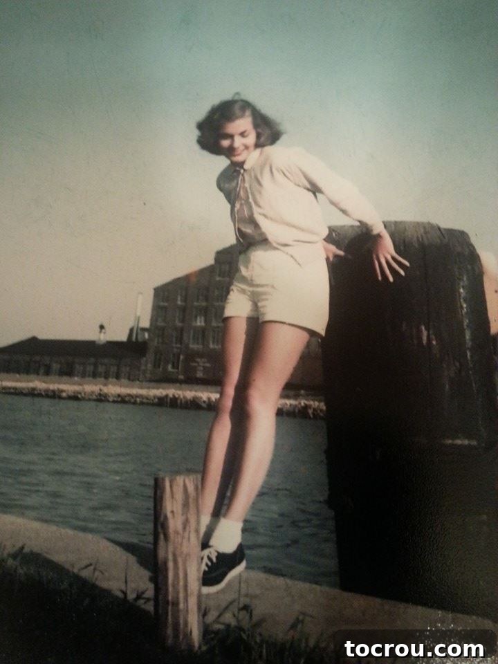 An old, black and white photograph of my grandmother as a teenager, joyfully playing on a pier in Lake Michigan, with waves crashing gently.