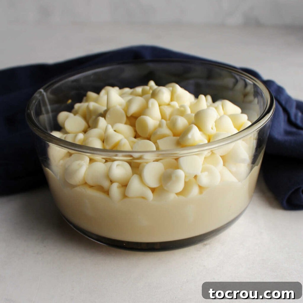 Vanilla baking chips and condensed milk in small glass bowl.