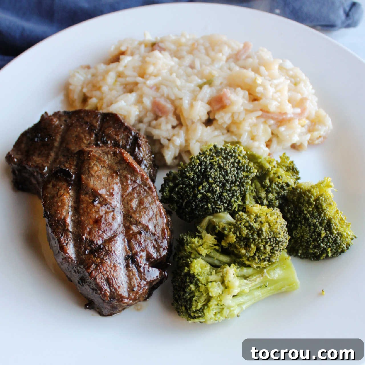 Savor the succulent flavors of Korean BBQ Venison Backstrap, served perfectly with steamed broccoli and fluffy rice for a wholesome meal. Dinner plate with grilled bul kogi style backstrap, broccoli and rice.
