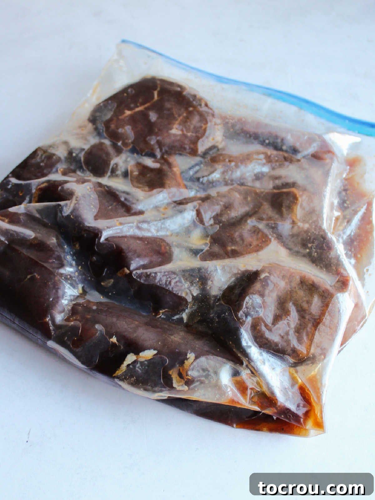 Chunks of venison backstrap soaking up the flavorful Korean BBQ marinade in a zipper bag, ready for grilling. Zipper bag filled with venison backstrap chunks and korean bbq style marinade.