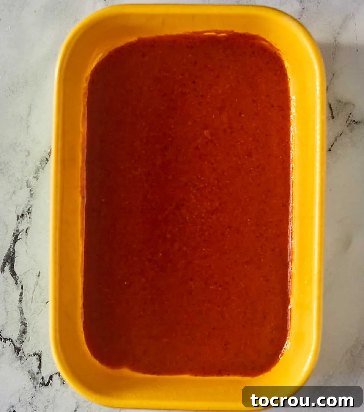 Enchilada Sauce in Pan A pan with freshly made red enchilada sauce at the bottom, prepared for layering with enchiladas.