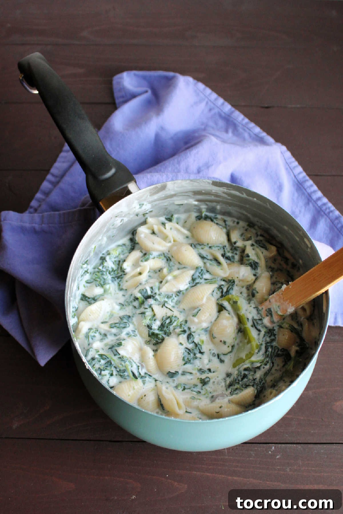 Velvety Spinach Macaroni Bake 4 Saucepan filled with creamy spinach mac and cheese, adorned with melted mozzarella and grated Parmesan cheese, glistening warmly.