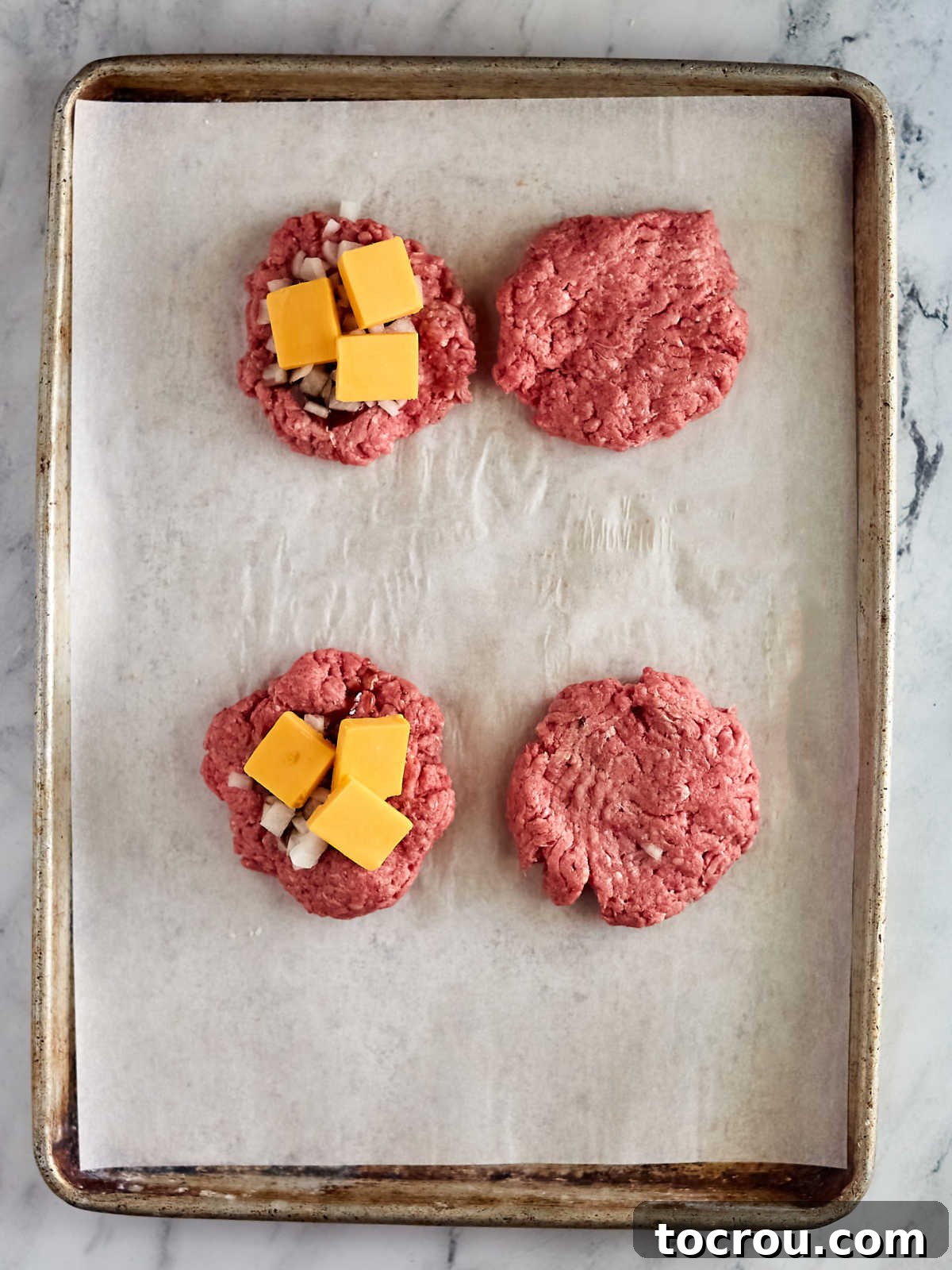 Maw-Maws Unexpected Burger Bliss 4 Four thick ground beef hamburger patties, two with onion, cheese and BBQ sauce on top ready to be topped by the other two to make stuffed burgers, showcasing the filling process.