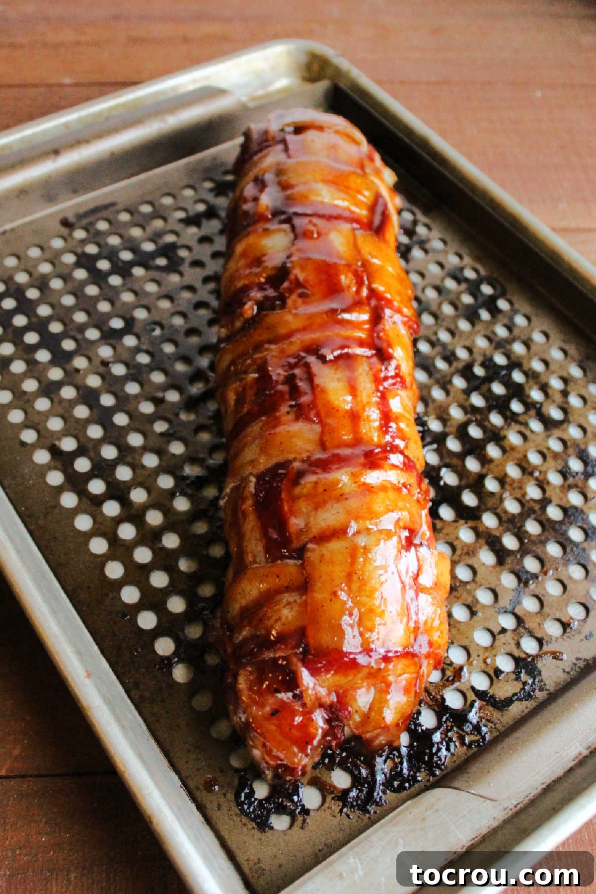 Cooked bacon explosion coated in BBQ sauce, fresh off the smoker. 