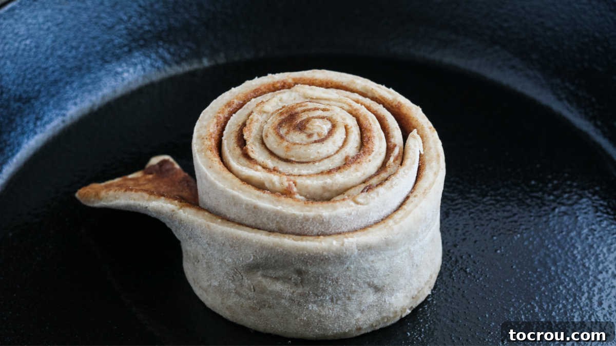 center of skillet cinnamon roll in middle of skillet with layers of cinnamon between layers of dough.