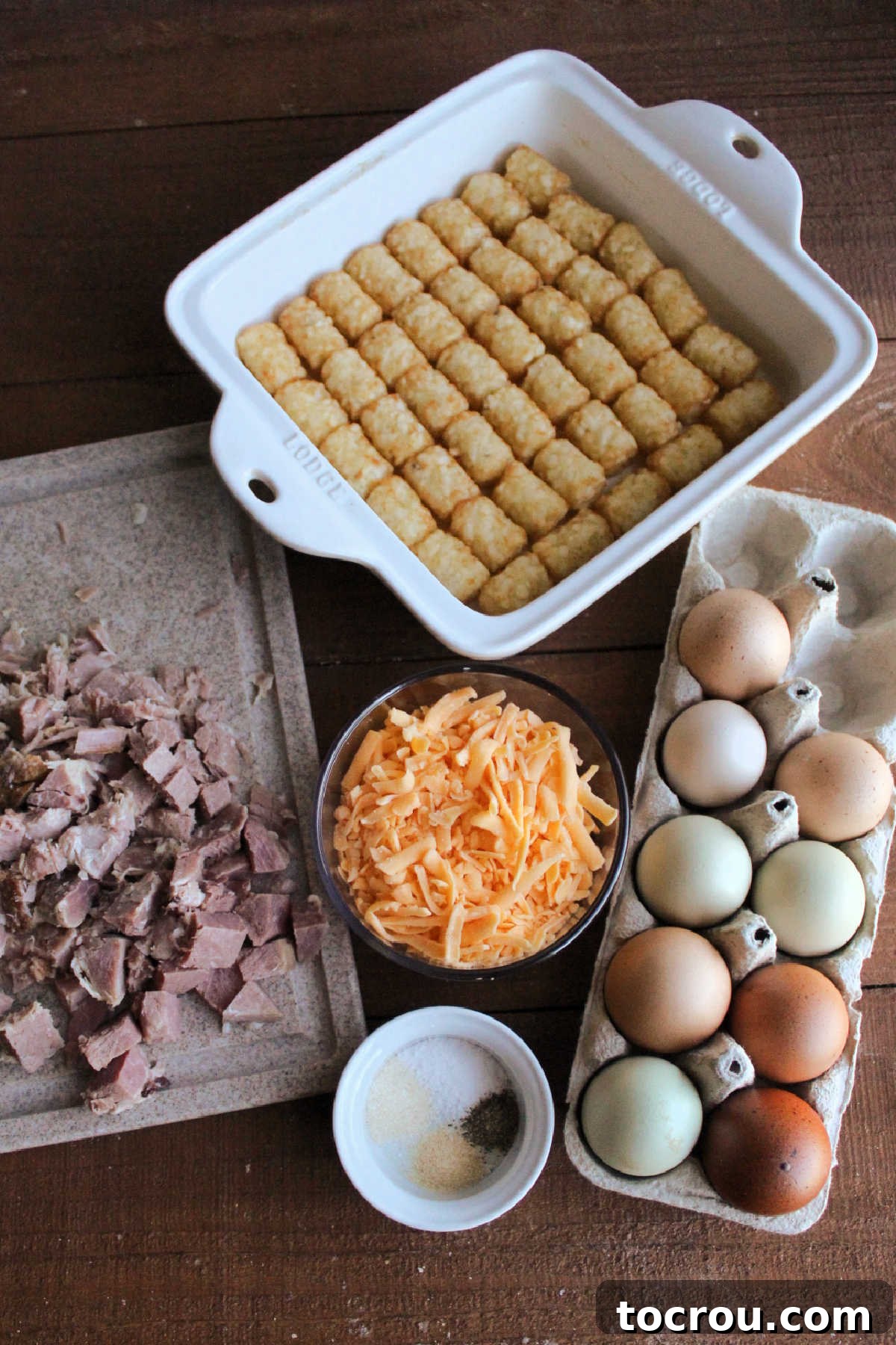 Tater Tot Casserole Ingredients All the essential ingredients for the casserole laid out: frozen tater tots, fresh eggs, shredded cheese, diced ham, and various seasonings.