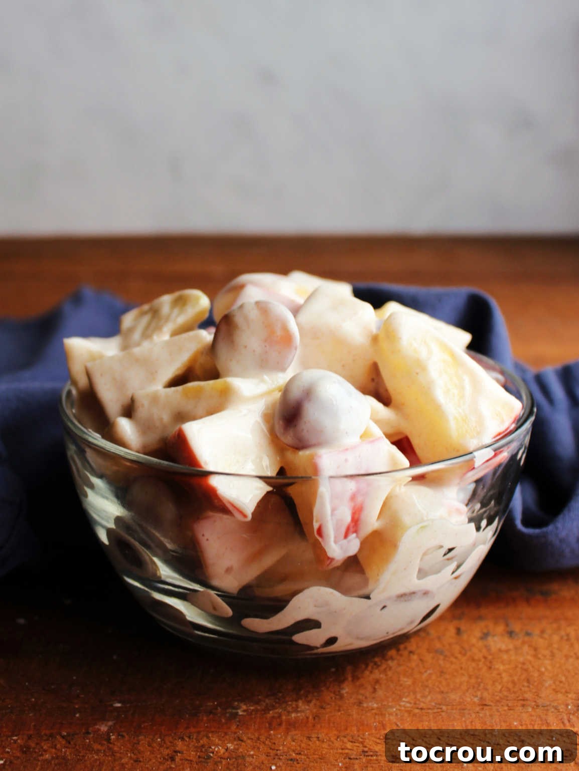 Side view of grape apple salad with cinnamon flecks. Side view of small glass bowl of grape apple salad showing cinnamon flecked creamy yogurt dressing, ready to eat.