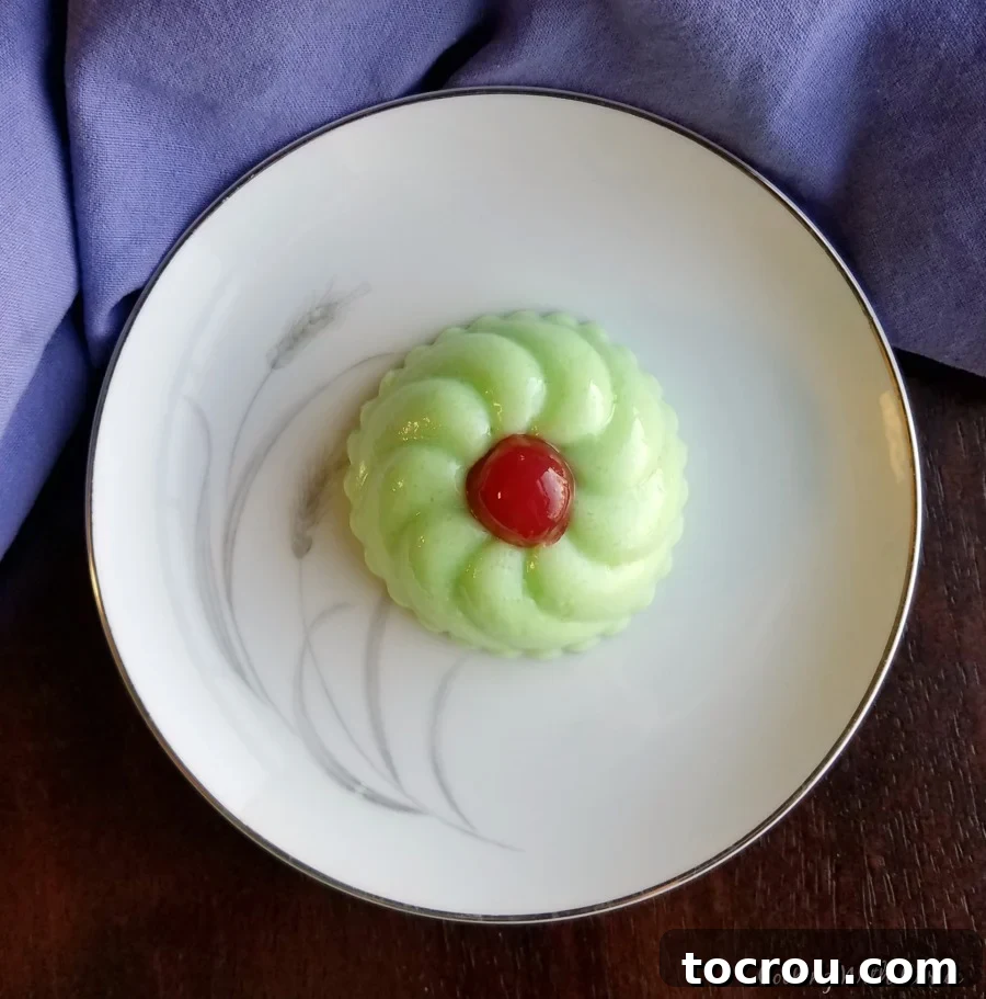 small molded jello salad on plate with red cherry on top