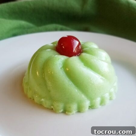 molded green jello salad with red maraschino cherry on top.