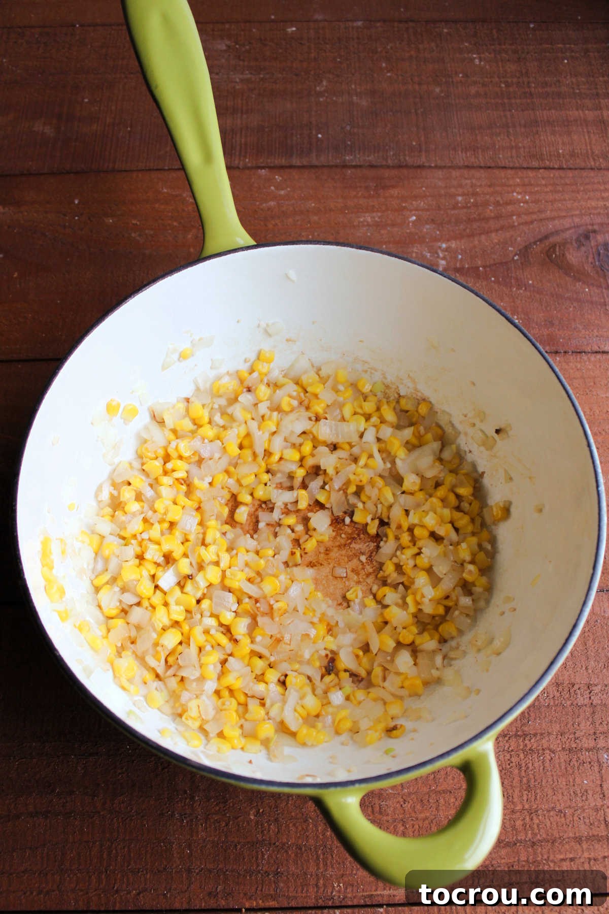 Fresh corn and diced onions sautéing in olive oil in a large pot, forming the flavorful base for the creamy crab chowder.