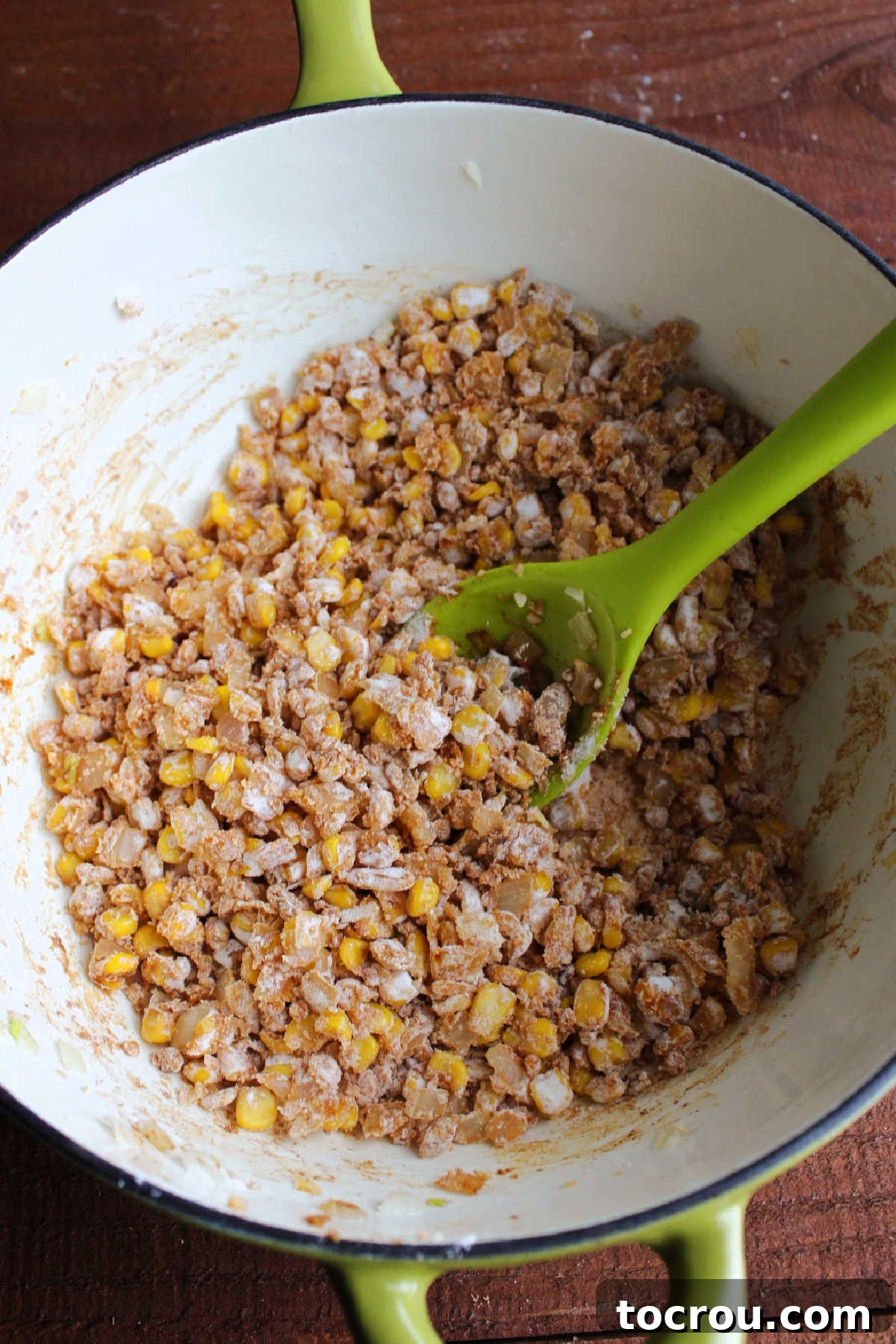 Diced corn and onions coated with Cajun seasoning, hot sauce, and flour, ready to be incorporated into the creamy chowder, showcasing the preparation of the roux.