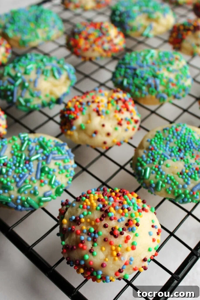 Sweetened condensed milk cookies rolled in sprinkles before being baked, cooling on wire rack.