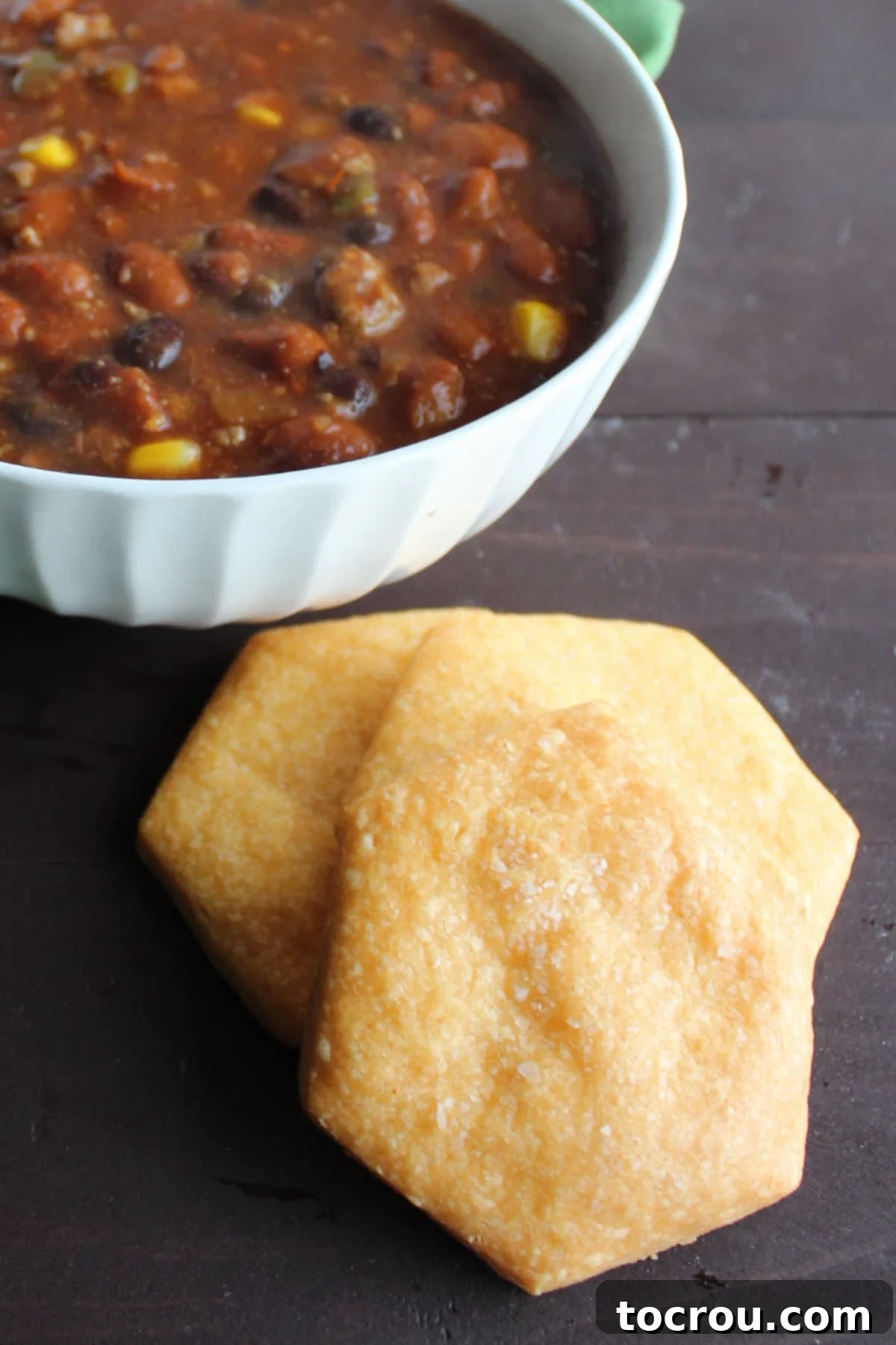 large homemade cheese crackers next to bowl of chili.