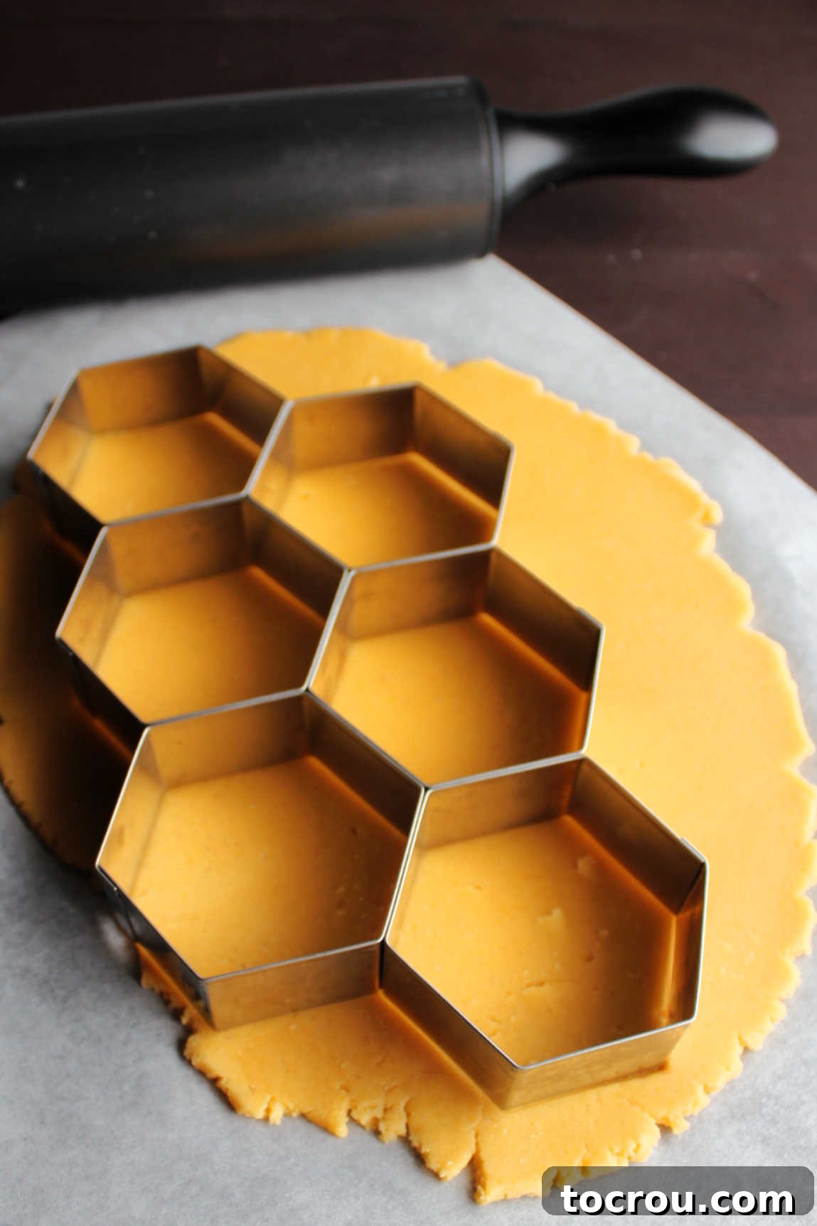 Biscuit cutter cutting multiple crackers out of cheese cracker dough.