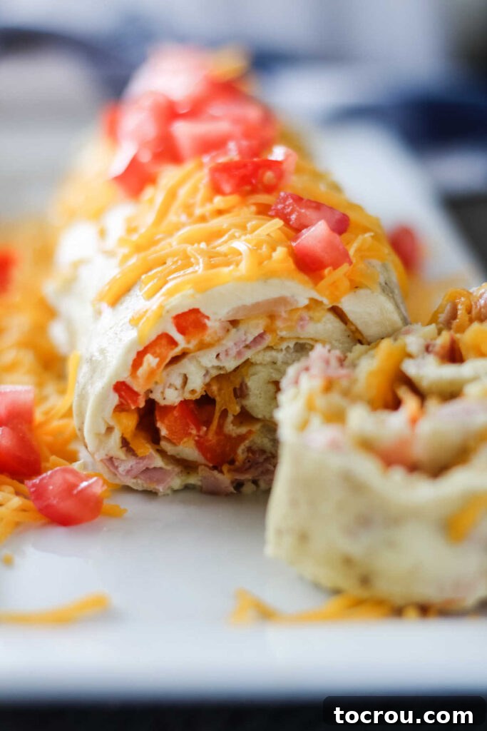 Denver Omelet Roll-Up 4 Looking at layers of spiraled denver omelet roll on plate showing ham, peppers and cheese inside.