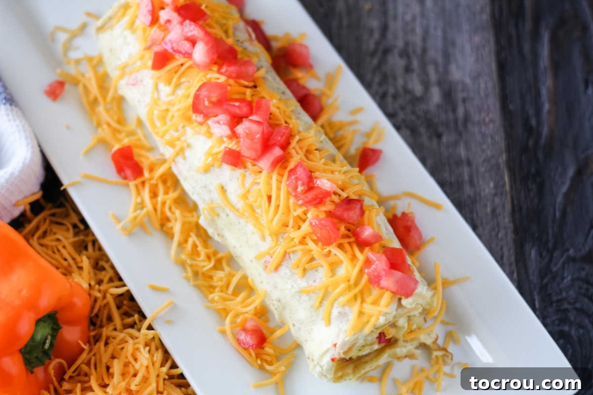 Denver Omelet Roll-Up 7 Rolled up sheet pan denver omelet topped with cheese and tomato on platter.