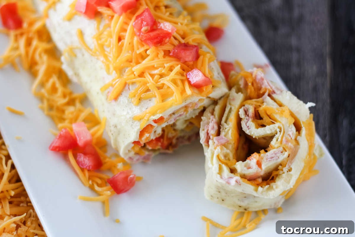 Denver Omelet Roll-Up 8 Cutting slice off of Denver omelet roll with layers of egg, cheese, peppers and more.